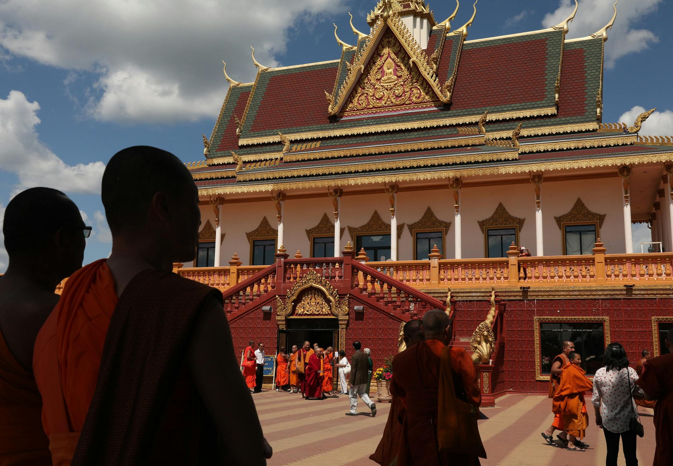 Monks stood in the shade as they took a break from the heat of the day at the Watt Munisotaram Saturday. ] ANTHONY SOUFFLE ï anthony.souffle@startribune.com Monks and members of the public celebrated the Inauguration of the Mucalinda Pond at the Watt Munisotaram, a local Buddhist temple, Saturday Aug. 12, 2017 in Hampton, Minn. The three-day celebration involves the sanctification of the Buddha statue in the Reflection pool.
