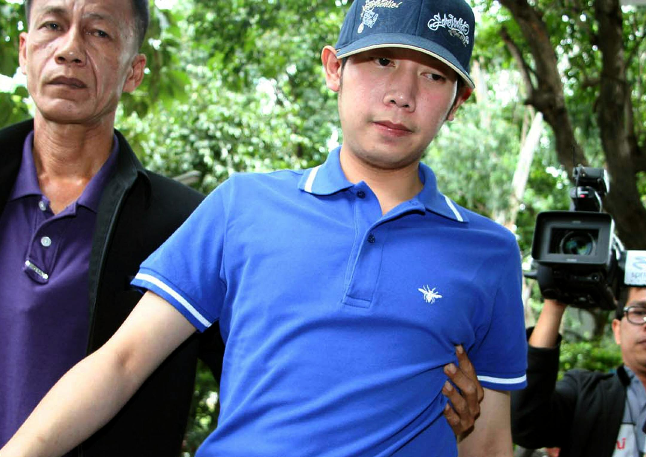 Vorayuth Yoovidhya, a grandson of late Red Bull founder Chaleo Yoovidhaya, is taken by a plain-clothes police officer for investigation Monday, Sept. 3, 2012 in Bangkok, Thailand. Vorayuth, believed to be in his late 20s, is suspected of driving a Ferrari that struck and killed a policeman and then dragged the officer's body down a Bangkok street in an early-morning, hit-and-run accident, police said Monday. (AP Photo) THAILAND OUT