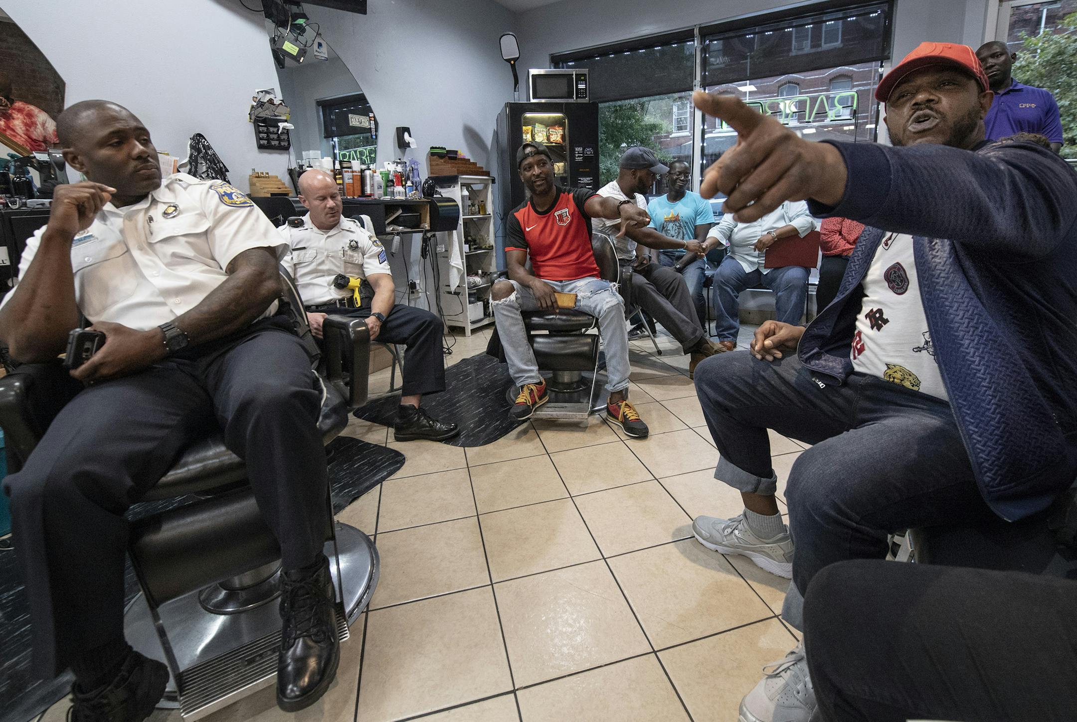 Malik King, right, speaks to police officers during a meeting called "Blades, Fades, and Engage" at the Philly Cuts barbershop in Philadelphia on September 17, 2018. A Philly police officer organized the event at a West Philly barbershop, where members of the community have an opportunity to chat directly with police officers. (Jose F. Moreno/Philadelphia Inquirer/TNS)