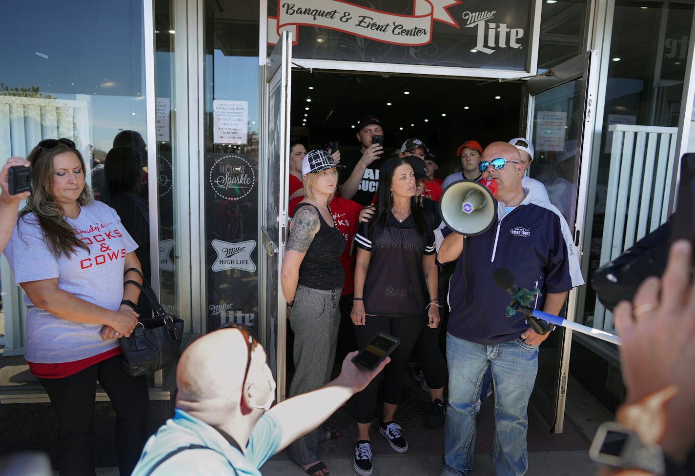 Kris Schiffler, right, the owner of Shady's Hometown Tavern in Albany, Minn. tells supporters outside his business that he's not opening his bar and grill Monday, May 18, 2020, on the advice of his attorney, after getting a call from Minnesota Attorney General Keith Ellison. (Brian Peterson/Star Tribune via AP)