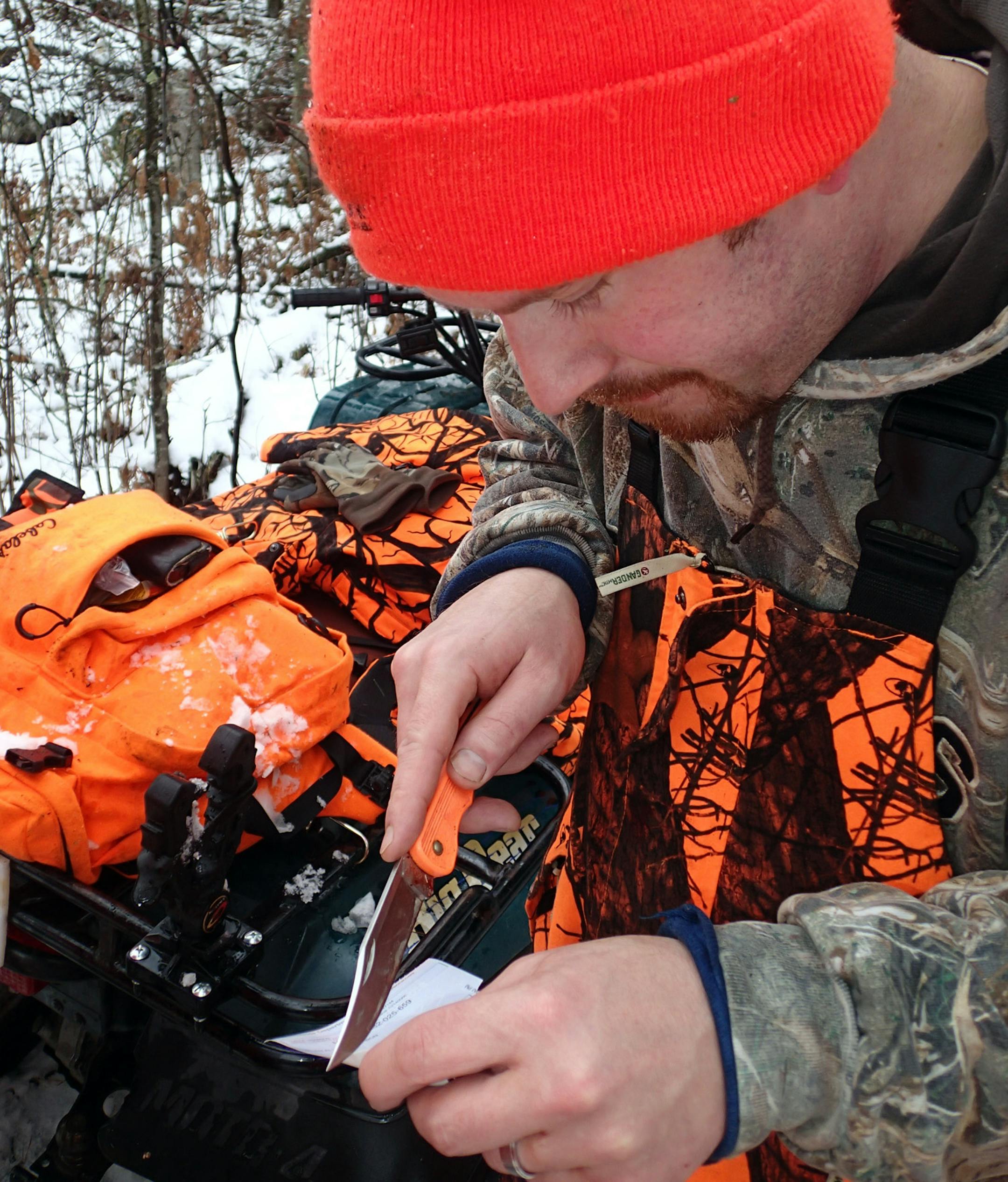Brian Anderson notches his DNR site tag after bagging a buck near Cook, Minn., on opening day of the whitetail season. Snowing early in the morning and even harder near sundown, the winterlike weather allowed for good visibility in the woods.