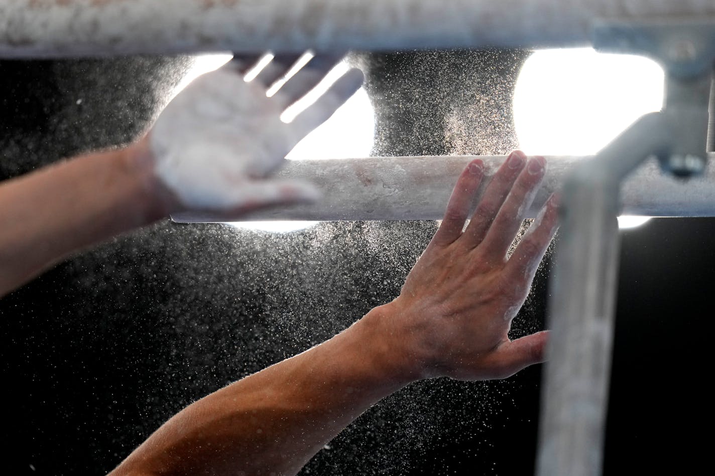 Artur Dalaloyan, of Russian Olympic Committee, puts chalk on the parallel bars during the men's artistic gymnastic qualifications at the 2020 Summer Olympics, Saturday, July 24, 2021, in Tokyo, Japan. (AP Photo/Gregory Bull)