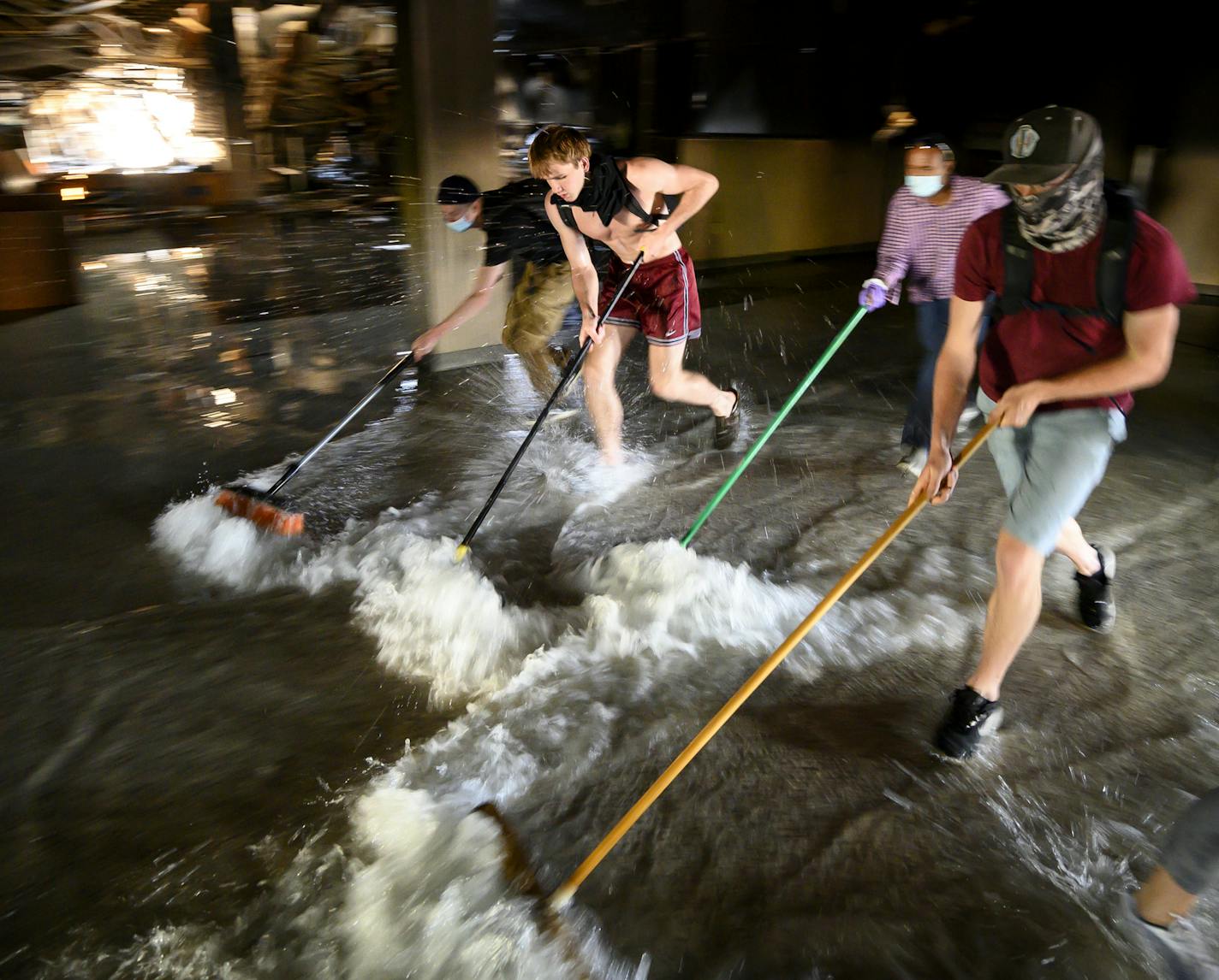 Dozens of protesters volunteered to sweep water to a storm drain from the burnt-down Wells Fargo across the street from the Minneapolis Police Fifth Precinct Saturday afternoon. ] aaron.lavinsky@startribune.com Protests continued in the wake of George Floyd's death in police custody on Saturday, May 30, 2020 in Minneapolis, Minn.