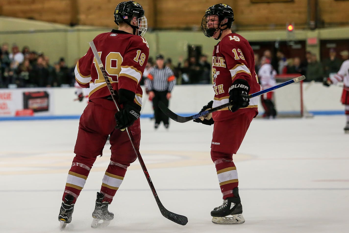 Lakeville South sophomore Cade Ahrenholz (19) and senior Riley Portnerore celebrate during the Class 2A, Section 1 final against Lakeville North on Feb. 28. Photo by Mark Hvidsten, SportsEngine