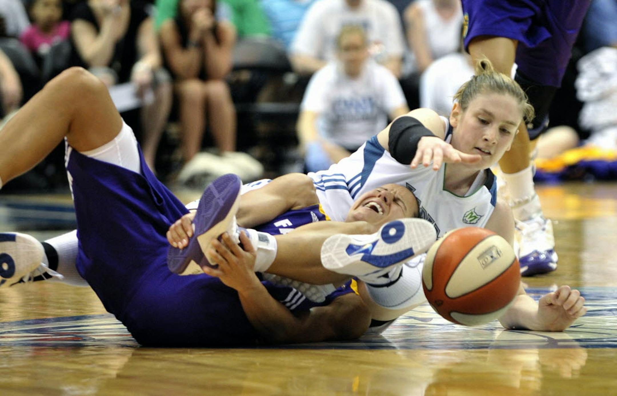 Minnesota's Lindsay Whalen, right, reaches for the ball as Los Angeles' Ticha Penicheiro reaches for her ankle as they go after a loose ball on Sunday.