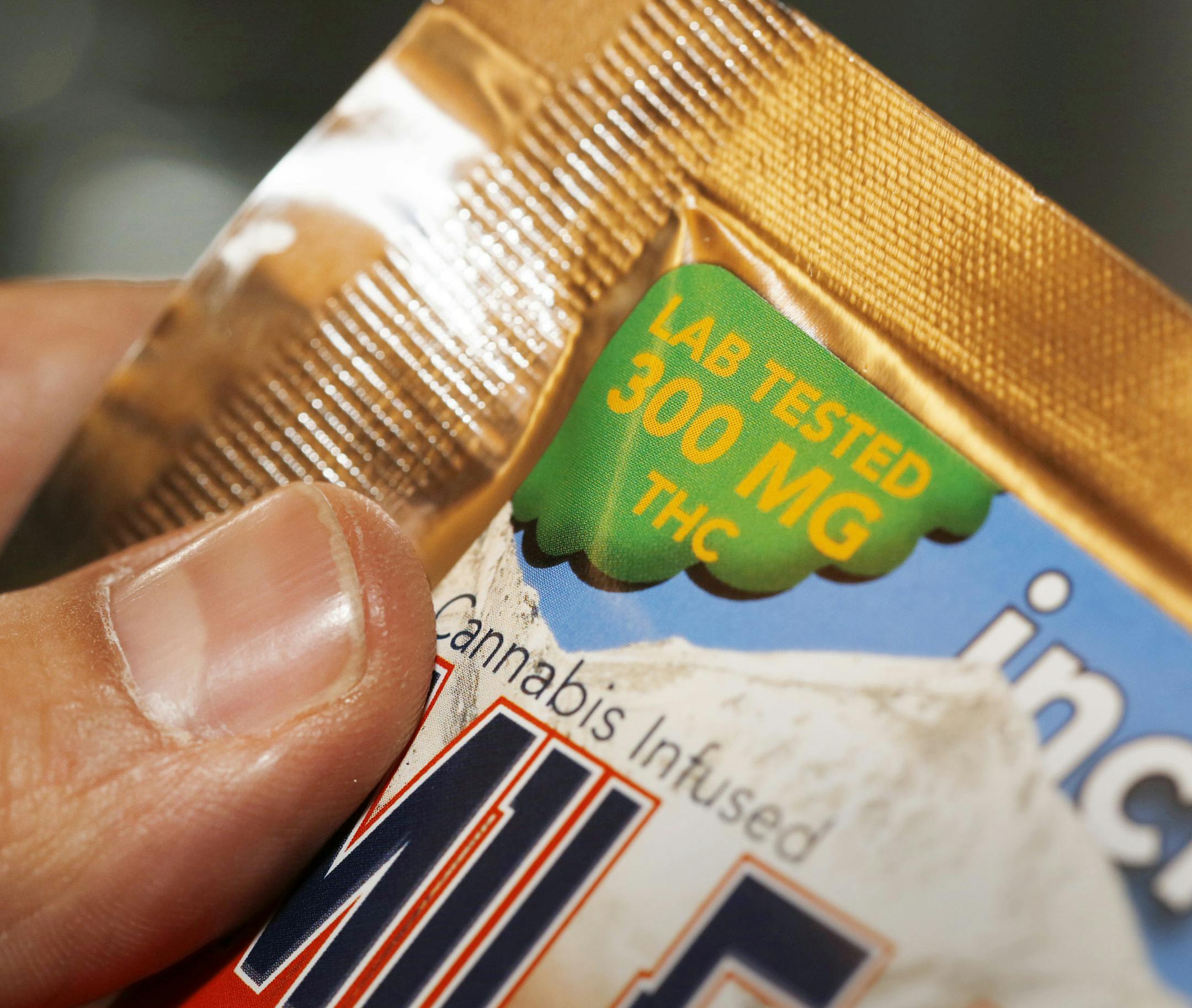FILE - In this April 18, 2014 file photo a caregiver points out the strength of an edible marijuana candy bar at a medical marijuana dispensary in Denver. In its entirety the candy bar is as strong at 30 marijuana joints. Colorado's marijuana experiment is under threat by the very popularity of eating it instead of smoking it, so the pot industry is joining health officials and state regulators in studying the problem of consumers eating too much too quickly. They plan to meet Wednesday, April 3