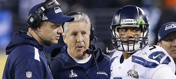 Seattle Seahawks offensive coordinator Darrell Bevell, from left, head coach Pete Carroll and quarterback Russell Wilson (3) talk during timeout again
