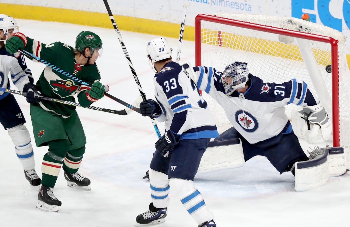 The Minnesota Wild's Mikael Granlund, left, steers a shot past Winnipeg Jets goalie Connor Hellebuyck (37) and into the net for a goal during the first period on Saturday.