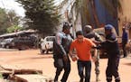Mali trooper assist a hostage, centre, to leave the scene, from the Radisson Blu hotel to safety after gunmen attacked the hotel in Bamako, Mali, Frid