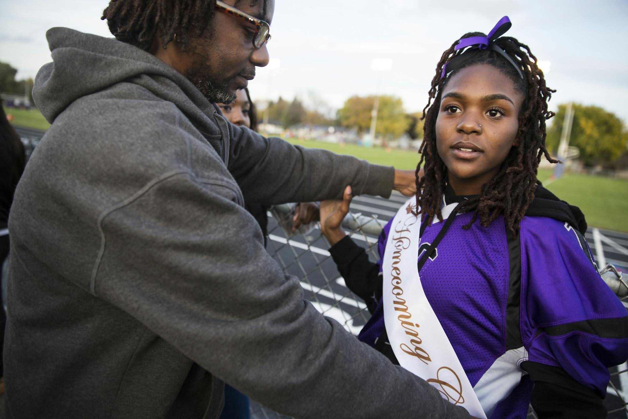 Homecoming court member Nia Ford gets some help adjusting her sash from her father Minkara Tezet.