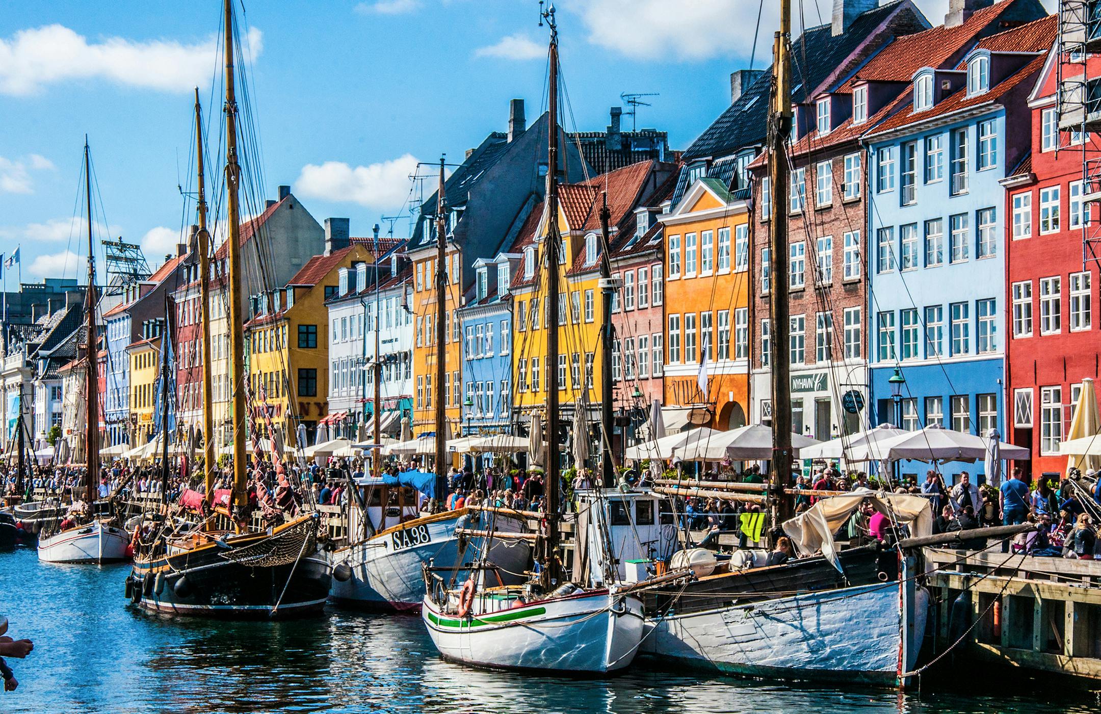 iStockphoto.com Copenhagen, Denmark - November 30, 2014: Crowds of people on the picturesque waterfront of Nyhavn. Coloured historic houses and blue water of the harbour canal.