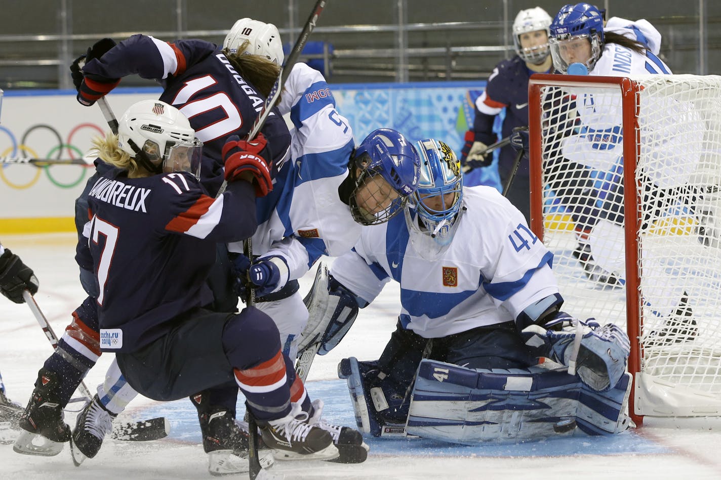 Goalkeeper Noora Raty of Finland reaches for the puck as Anna Kilponen of Finland (5) keeps Meghan Duggan of the Untied States (10) and Jocelyne Lamoureux of the Untied States (17) away from the gaoll during the third period of the women's ice hockey game at the Shayba Arena during the 2014 Winter Olympics, Saturday, Feb. 8, 2014, in Sochi, Russia. (AP Photo/Matt Slocum)