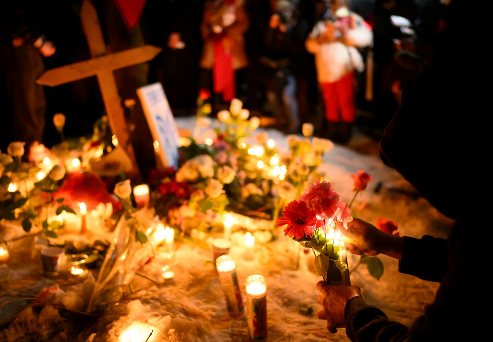 Vigil goers place flowers on a memorial for Renee Nicole Good, 37, who was shot and killed by federal law enforcement earlier in the day on Portland Avenue at East 34th Street  Wednesday, Jan. 7, 2026 in Minneapolis.