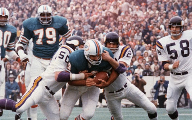 FILE - In this Jan. 13, 1974, file photo, Miami Dolphins' Larry Csonka drives between Minnesota Vikings' Jeff Siemon (50) and Paul Krause for one of h