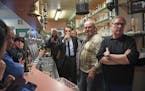 French centrist presidential election candidate Emmanuel Macron drinks a glass of beer as he speaks behind the bar counter, next to cafe owner Marc Pi