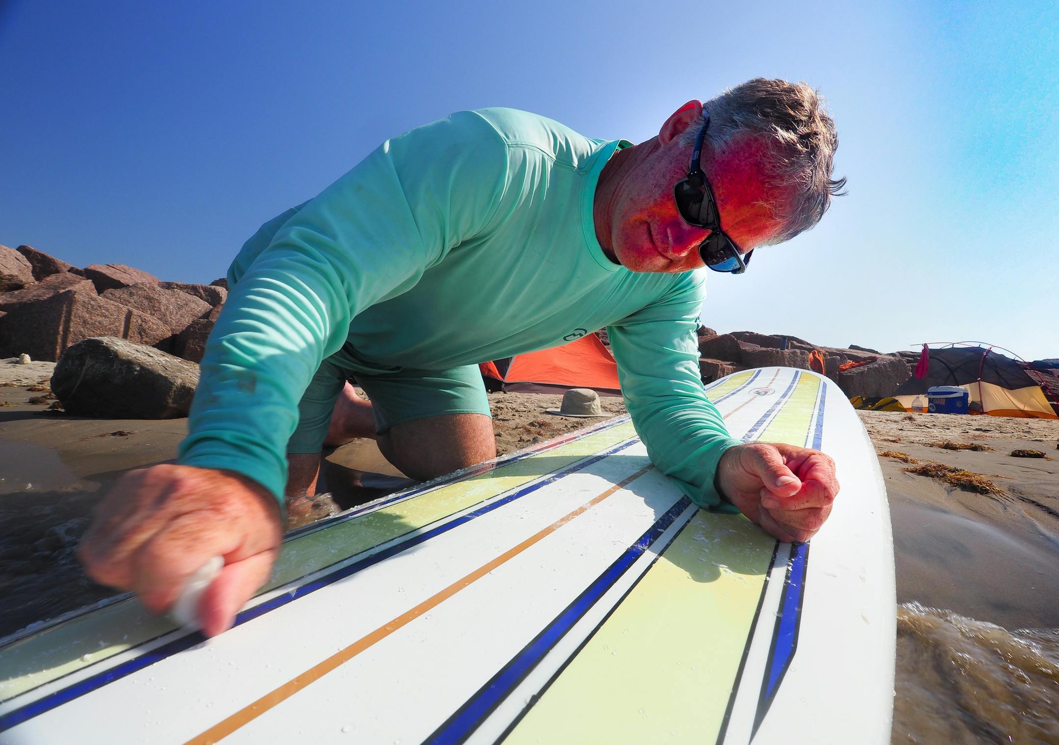 Erich Schlegel waxes his surfboard during a beach camping trip at Mansfield Cut in May 2018. (Pam LeBlanc/American-Statesman/TNS)