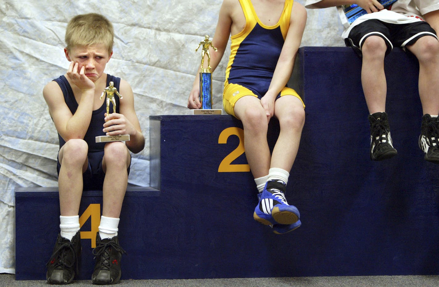 Jimmy Cates, 8, of Prior Lake is not too happy about posing with his trophy after competing in a youth wrestling tournament at Prior Lake High School on Saturday, January 3, 2004. But having just competed in his first wrestling tournament ever and after only three practices, Jimmy did remarkably well, said his mother Terri Cates. Jimmy placed fourth out of four boys in his age group and ability. ORG XMIT: MIN2017050914371252