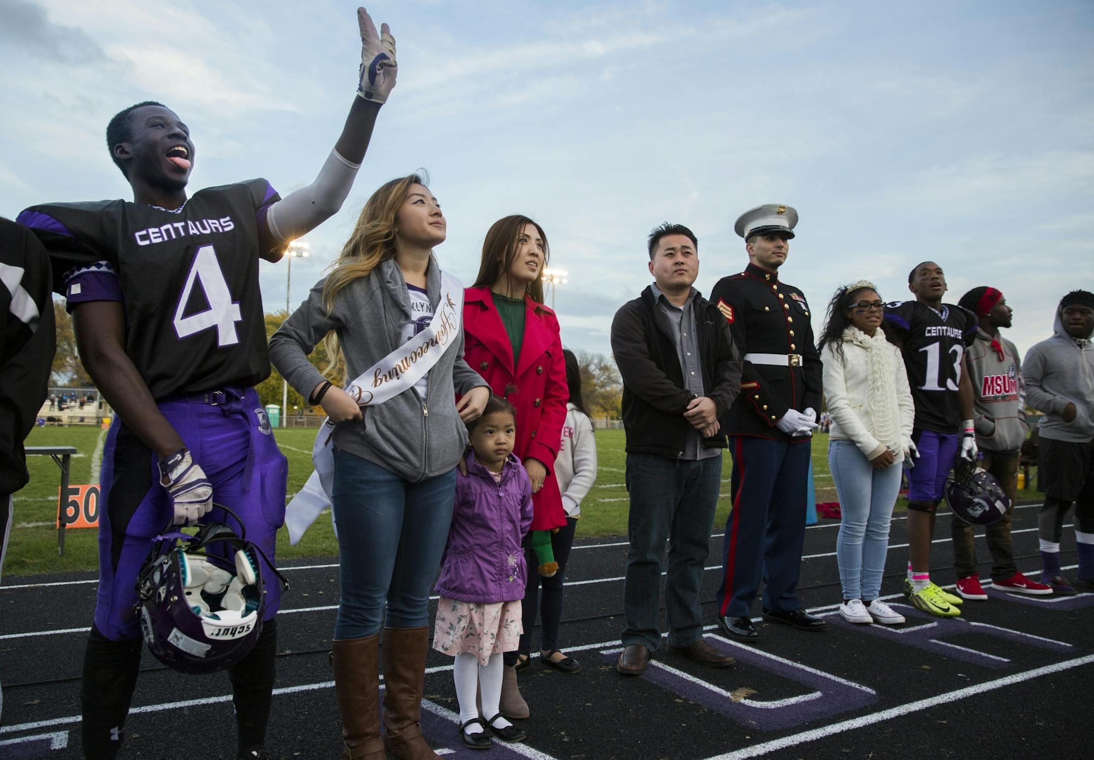 Homecoming court members Molubah Seley, from left, and Jade Yang stand together with family and the rest of the court during halftime.