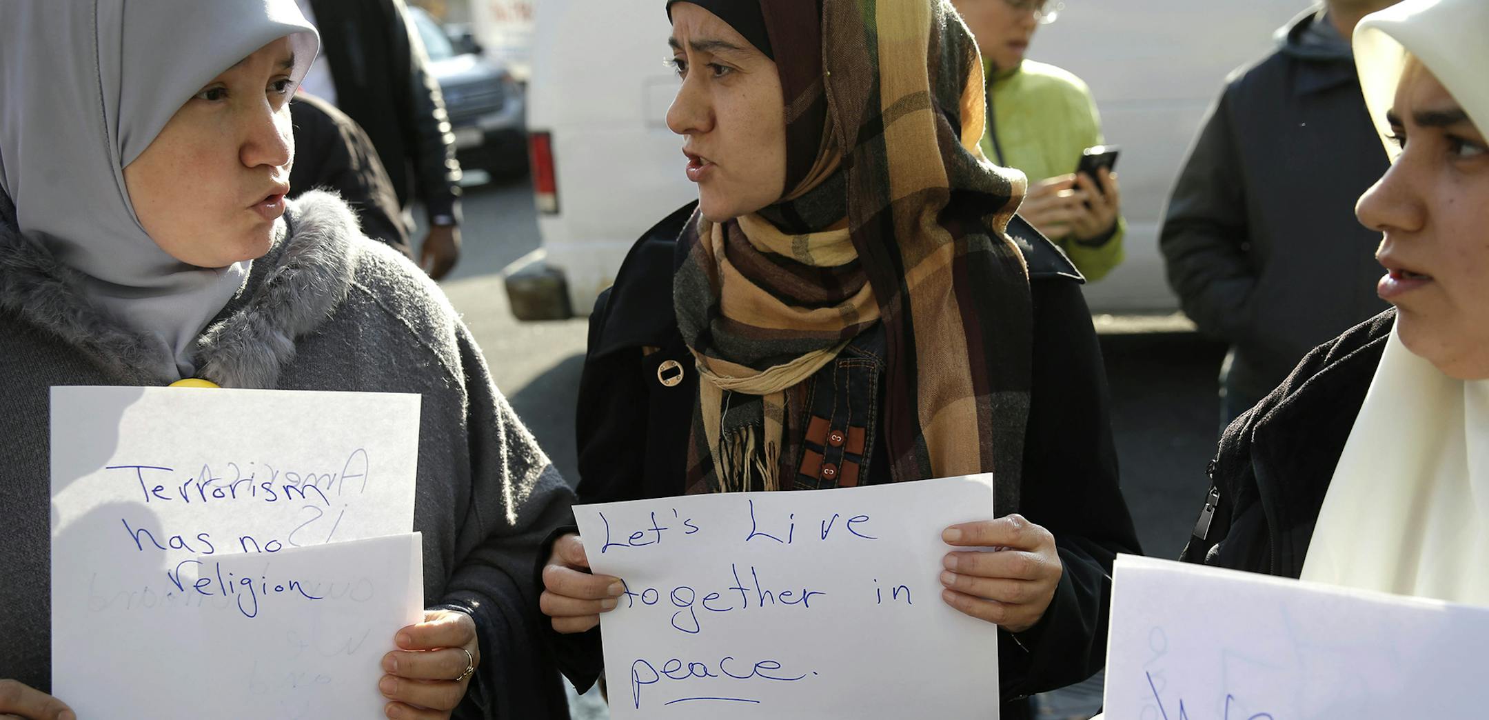 Amina Ismail, left, Fatima Amaziane, center, and Dalia Abdallah hold signs during a news conference in the Queens borough of New York, Thursday, Dec. 10, 2015. The news conference was called to express opposition to hate crimes and rhetoric, particularly in light of a recent attack in the neighborhood that police are investigating as a hate crime. Advocacy groups believe there has been a spike in anti-Muslim incidents across the United States in recent weeks that can be linked to last week's mas
