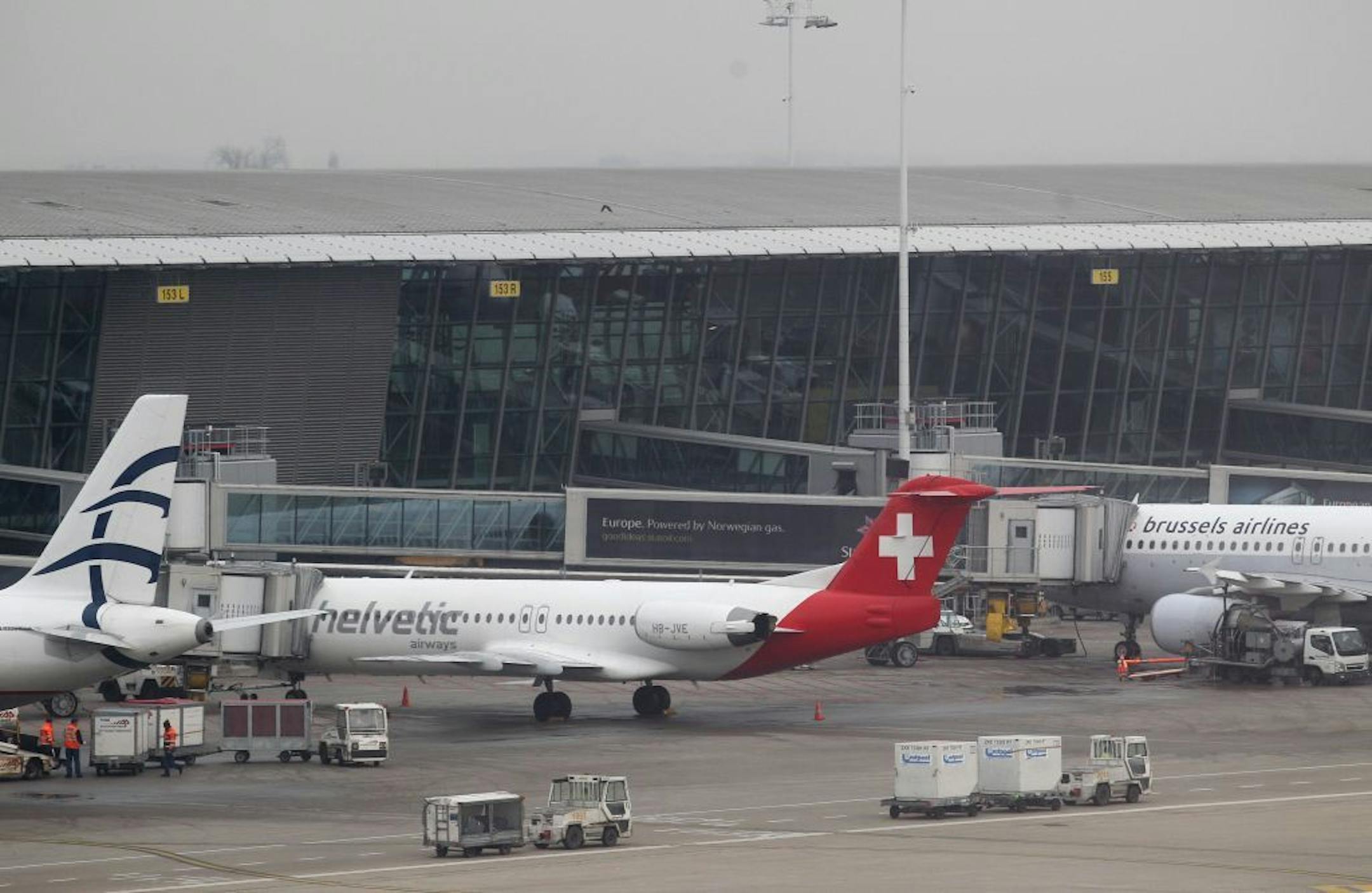 Baggage carts make their way past a Helvetic Airways aircraft from which millions' of dollars worth of diamonds were stolen on the tarmac of Brussels international airport, Tuesday, Feb. 19, 2013. Eight armed and masked men made a hole in a security fence at Brussels' international airport, drove onto the tarmac and snatched millions of dollars' worth of diamonds from the hold of a Swiss-bound plane without firing a shot, authorities said Tuesday.