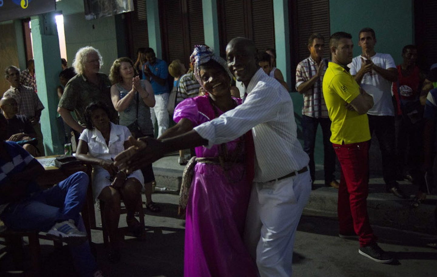 In this March 21, 2015 photo, seniors dance in the street for tourists at night in Santiago, Cuba. Life in Cuba in 2015 is a race between hope and desperation, as a staggering economy pushes some towards new ways of living and others toward hopelessness, anger and emigration. (AP Photo/Ramon Espinosa)