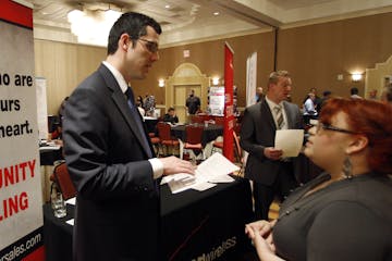 In this Oct. 4, 2011 photo, Blake Andrews with Verizon, left, visits with prospective employees during a job fair, in San Antonio. The United States a