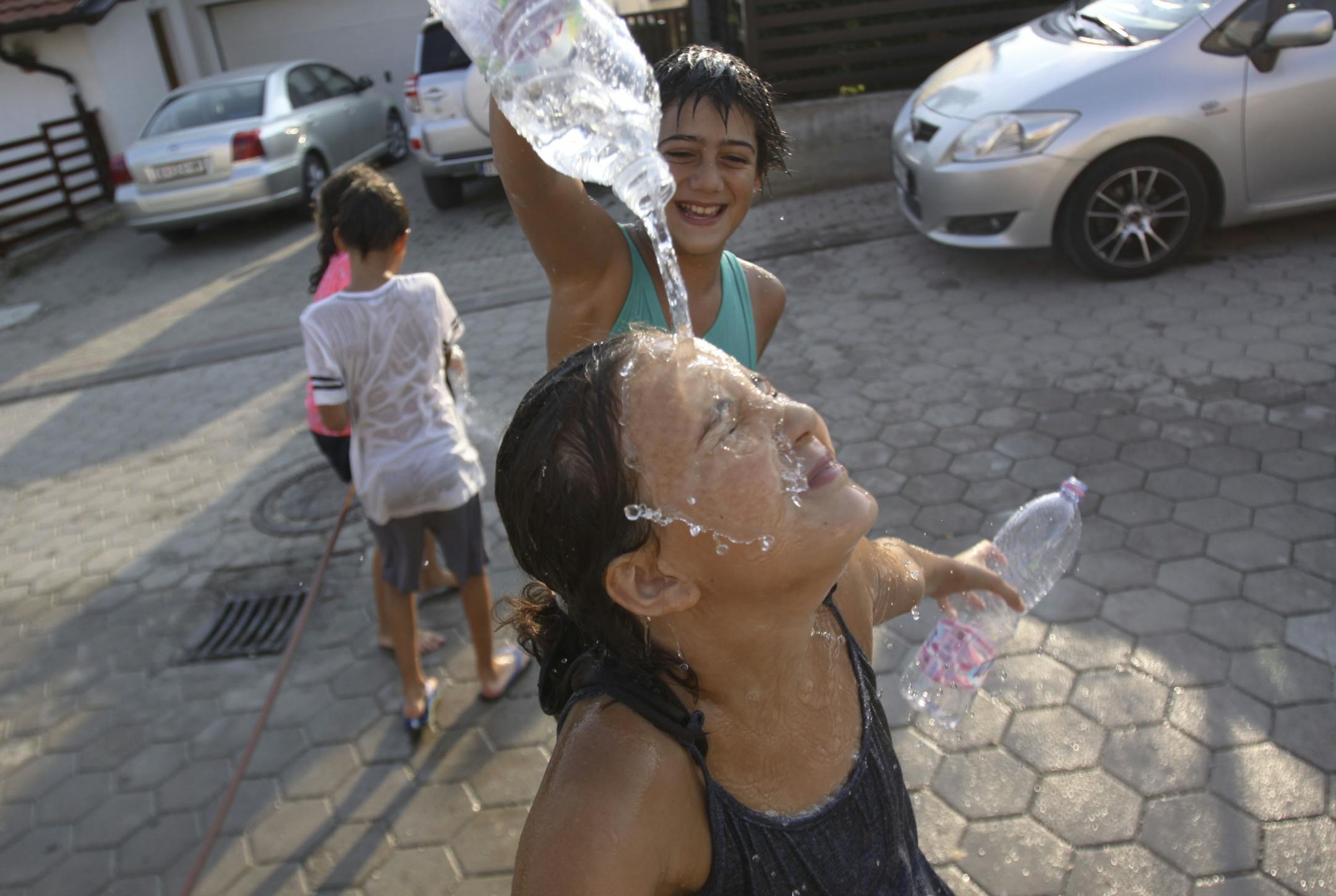 Children pour water over each other as they try to refresh themselves on a hot day in Hajvali 15 km (12 miles) from capital Pristina on Sunday, July 19, 2015. Europe's heat wave has pushed the mercury to levels as high as 40 degrees Celsius, 104 fahrenheit .