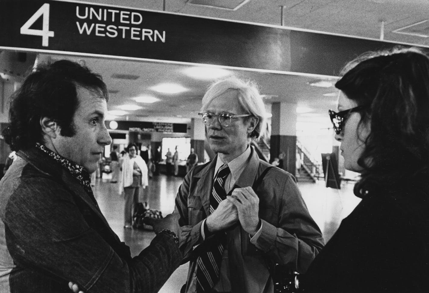 Andy Warhol, center, and a member of his entourage known as Lady Anne Lambton, right, were met at Minneapolis-St. Paul International Airport by art dealer Gordon Locksley, September 17, 1975. Minneapolis Tribune photo by staff photographer Earl Seubert.