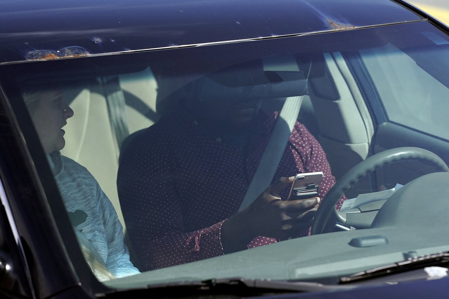 This April 24, 2019 photo shows one of several distracted drivers using a cell phones and spotted by Eagan, Minn., police officers during the "Busted by the Bus" initiative in Egan, Minn. The Minnesota Department of Public Safety is trying to raise awareness about a new law that takes effect Aug. 1 that requires drivers to use hands-free devices to talk on the phone while driving. The law bars motorists from holding and using cell phones or other wireless devices while driving. (Anthony Souffle/