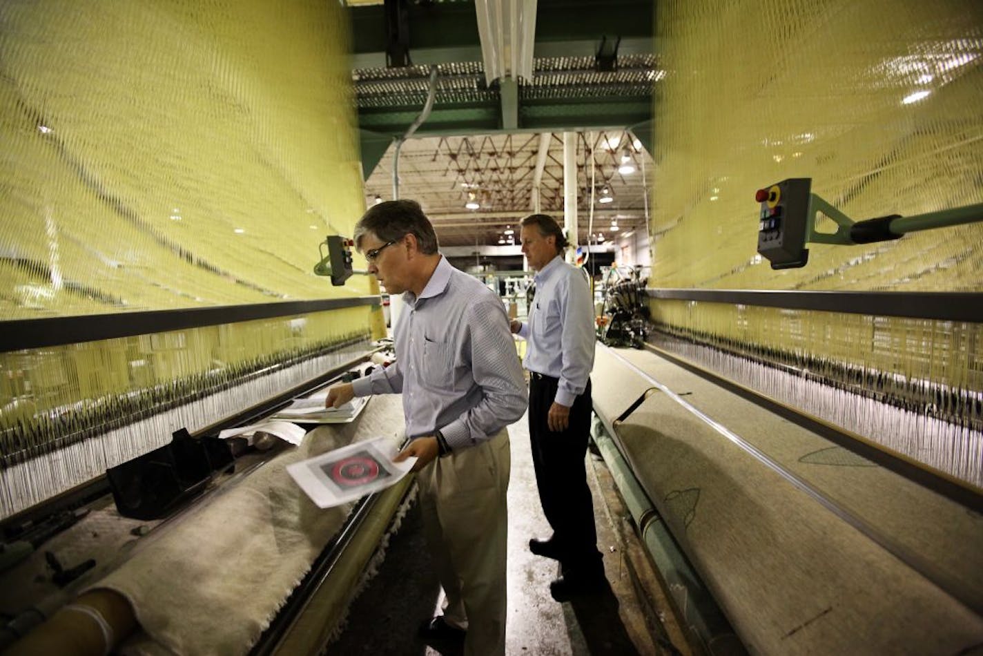 File photo: Cousins Paul, left, and Chuck Mooty have purchased the closed Faribault Woolen Mills factory and plan to reopen it soon. During a tour of the historic building in Faribault, they stood between two weaving looms that were stopped in mid-production of a blanket when the business shut down.