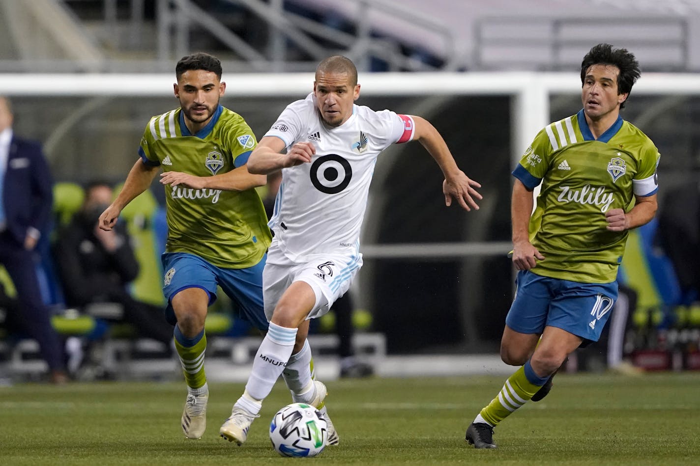 Minnesota United midfielder Osvaldo Alonso (6) dribbles in front of Seattle Sounders midfielder Cristian Roldan, left, and midfielder Nicolas Lodeiro during the second half of an MLS playoff Western Conference final soccer match, Monday, Dec. 7, 2020, in Seattle. (AP Photo/Ted S. Warren)