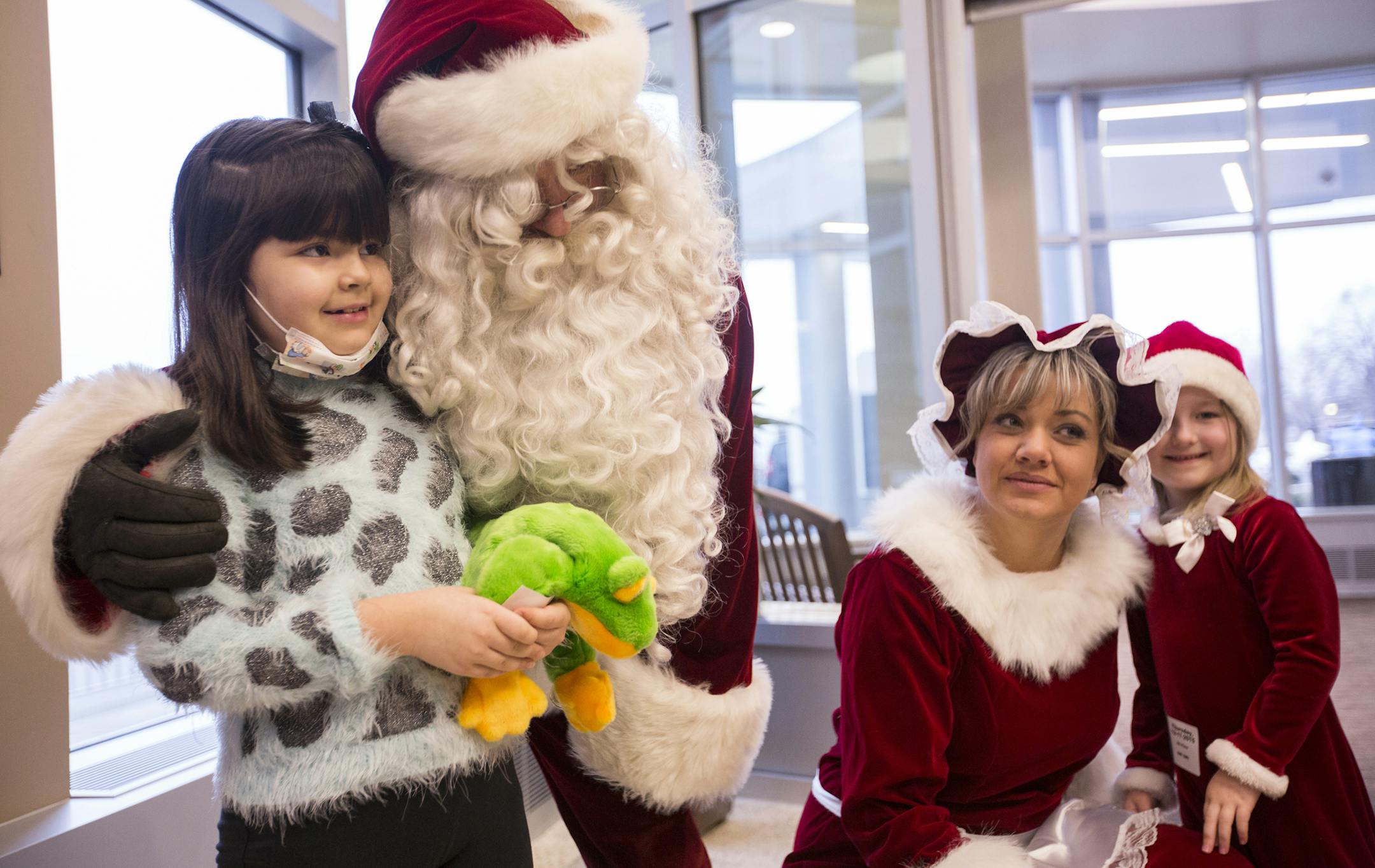 Santa Claus, played by retired St. Paul police officer Tim Bradley, poses for a photo with Brianna Guerra, from left, 7, Mrs. Claus played by St. Paul police officer Amy Rahlf, and Kate Young, 5, during a visit to patients at Children's Hospitals in St. Paul on Thursday, December 17, 2015. ] (Leila Navidi/Star Tribune) leila.navidi@startribune.com BACKGROUND INFORMATION: St. Paul Police Department members visited patients at Children's Hospitals St. Paul with Santa Claus, Mrs. Claus, elves (all