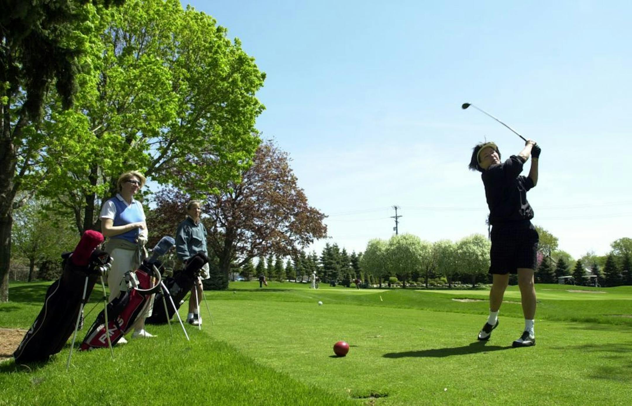 Ginger Gieler hits of the 13th tee as Virginia Hickey watches as their foursome continues their round of golf on ladies day at the Town and Country Club in St. Paul.
