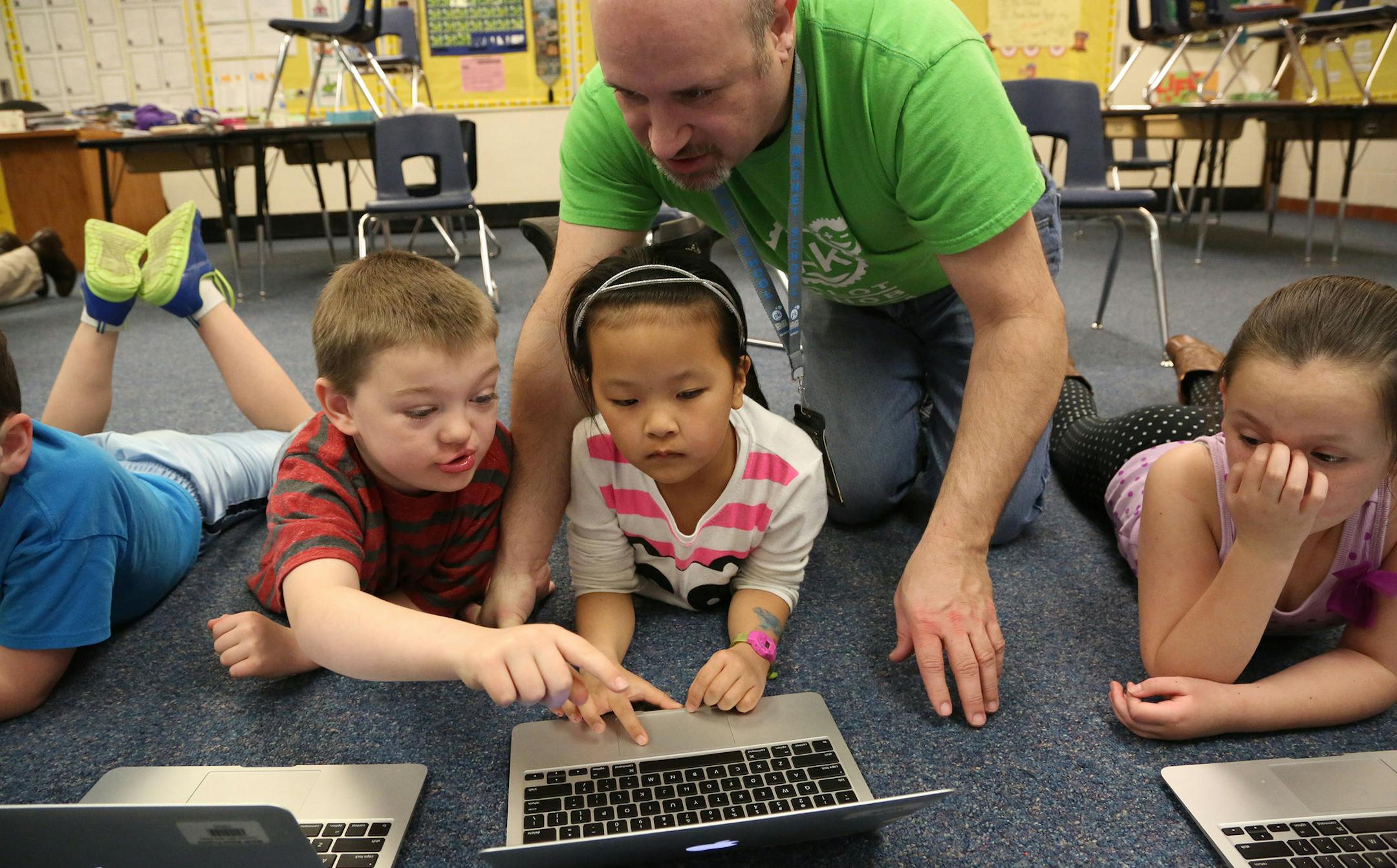 Logan Conright, 8, Jeffrey Oppenheim, second grade teacher, helped Hannah Sweeney, 8 find educational games on her laptop during spring break school. ] (KYNDELL HARKNESS/STAR TRIBUNE) kyndell.harkness@startribune.com Pilot Knob Elementary in Eagan Min., Thursday, March 31, 2014.