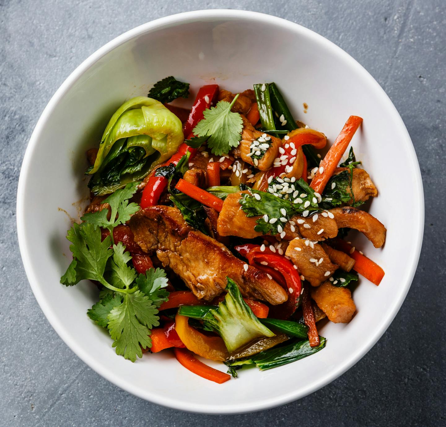 Chicken meat with vegetable in bowl stir fry on wok on concrete background