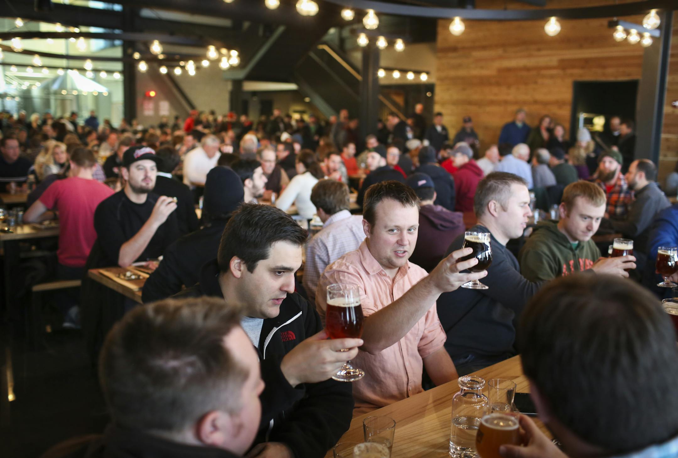 Adan Perez and Cory Tranby raised their beers in a toast with friends at the Surly brew-pub tap room public grand opening in Minneapolis, Minn. on Friday, December 19, 2014. The group of "IT guys who love beer" had ran into each other on the Lightrail on their way to the brew-pub. ] RENÉE JONES SCHNEIDER reneejones@startribune.com