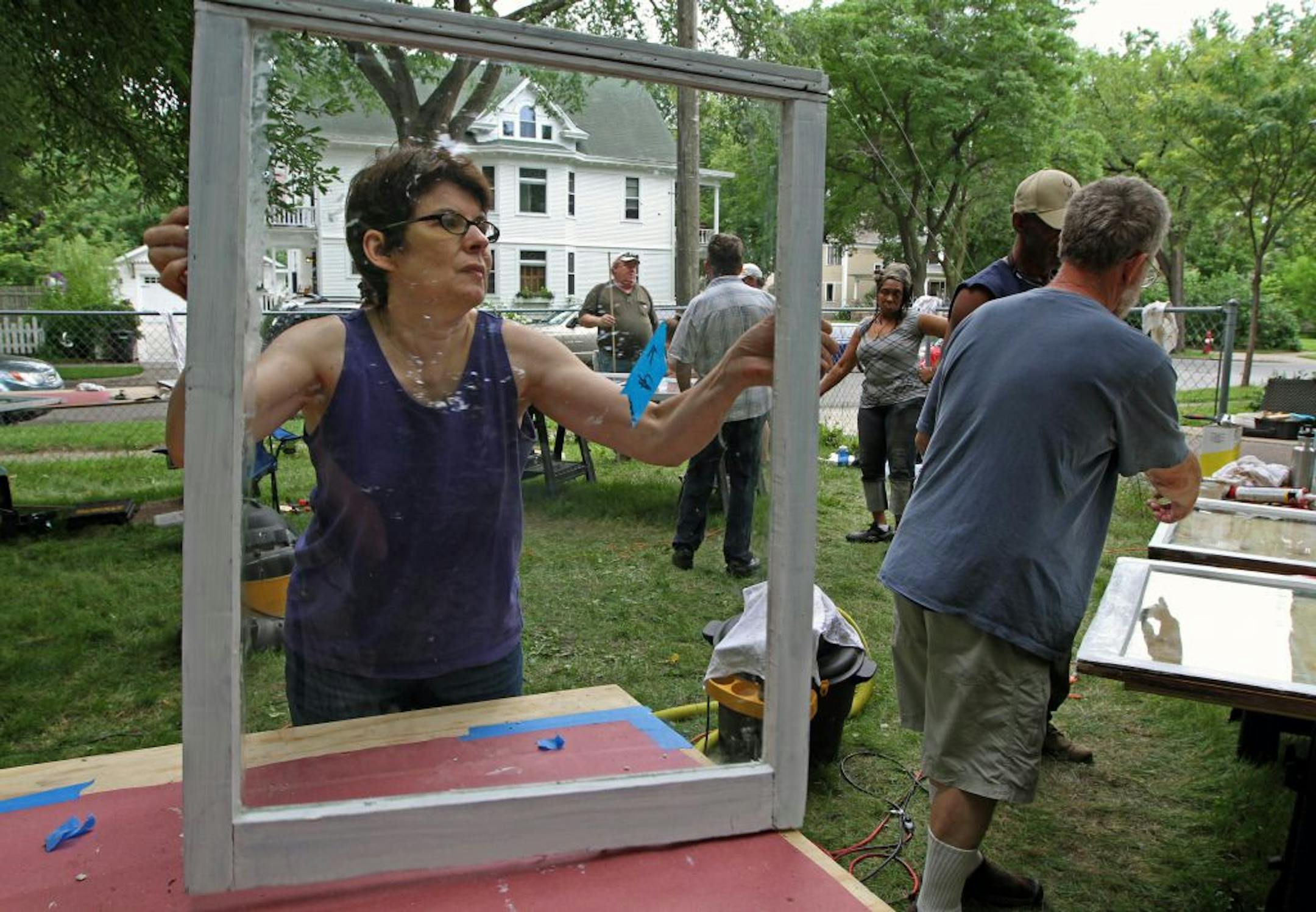 (left to right) Volunteer Paula Horan of Minneapolis, moved a window as a group of homeowners learned practical home restoration skills in a hands-on workshop in the old Highland neighborhood of near north Minneapolis on 6/23/12. The volunteers took out windows from a home at 1700 Emerson Ave North, repaired broken glass, installed new caulk and weatherstrip and painted the windows during the restoration workshop.