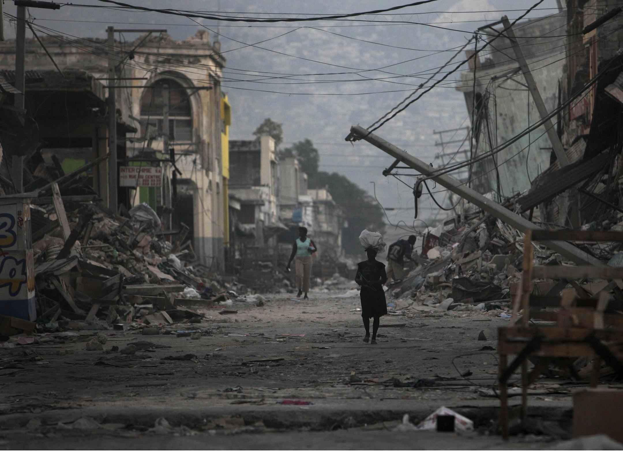 FILE - This combo of two photos shows a Jan. 20, 2010 file photo, top, of a street devastated by the 7.0 earthquake that struck one week before in Port-au-Prince, Haiti, and a photo taken five years later, on Jan. 10, 2015, of the same location. Haiti's government put the death toll at 316,000, while some estimates were lower. An exact accounting was impossible given the widespread devastation. (AP Photo/Gregory Bull, Dieu Nalio Chery, File)