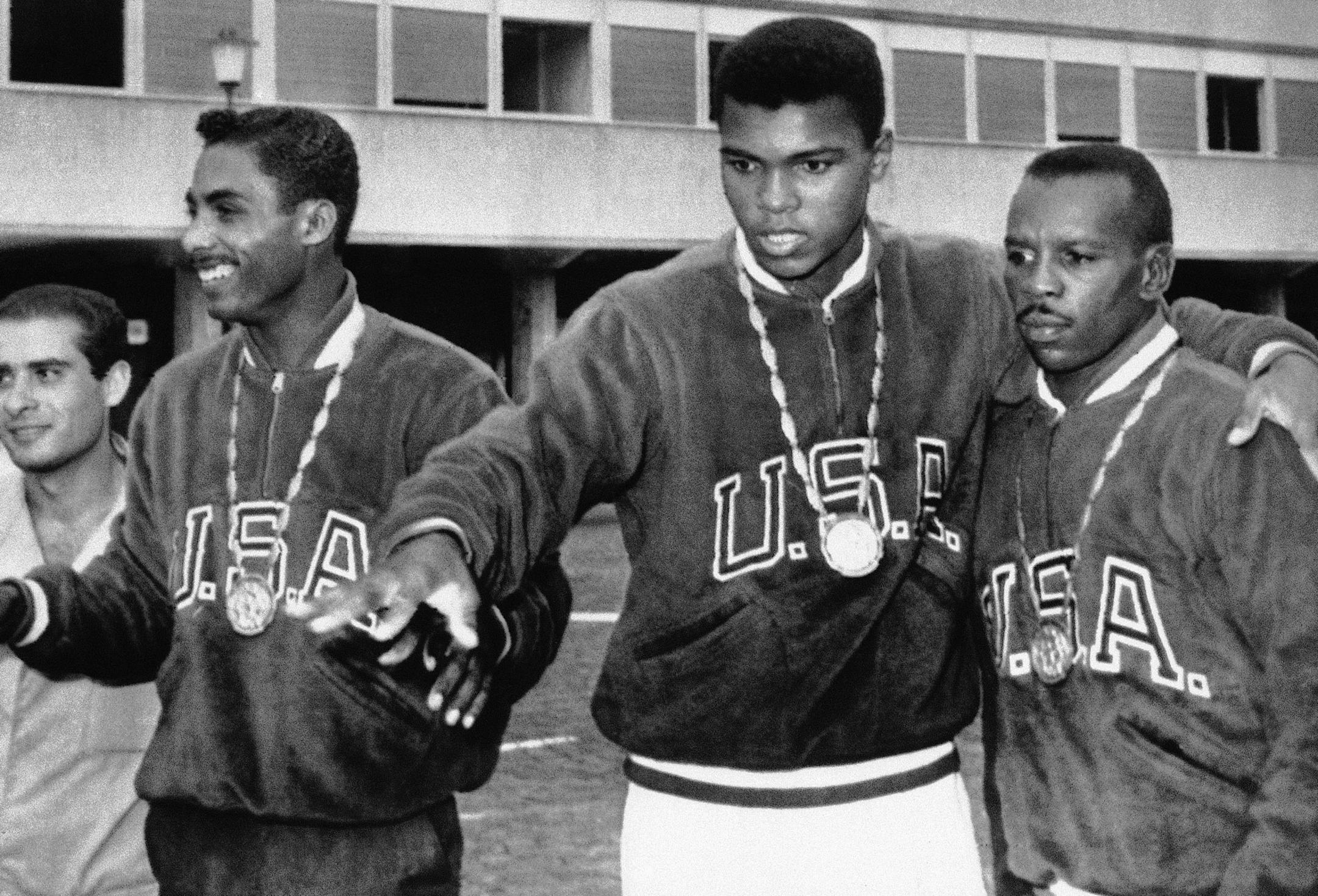 A trio of U.S. boxers wear gold medals at the Olympic village in Rome, Sept. 6, 1960. From the left are: Wilbert McClure of Toledo, Ohio, light middleweight; Cassius Clay of Louisville, Kentucky, light heavyweight; and Edward Crook of Fort Campbell, Kentucky, middleweight. (AP Photo) ORG XMIT: APHS281682