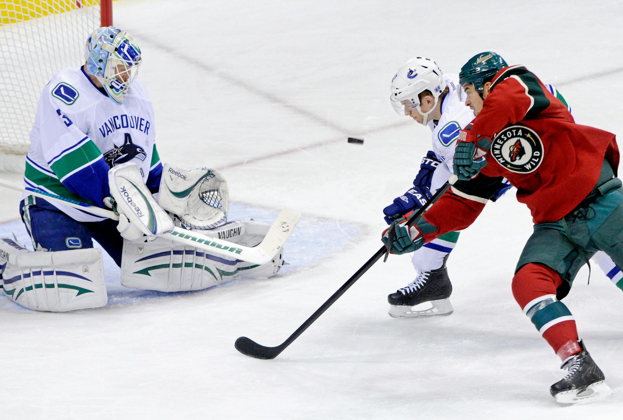 Vancouver Canucks' Alexander Sulzer, of Germany, second from right, pressures Minnesota Wild's Devin Setoguchi, right, after Canucks goalie Cory Schneider stopped a shot in the first period of an NHL hockey game Thursday, Nov. 3, 2011, in St. Paul, Minn. (AP Photo/Jim Mone)