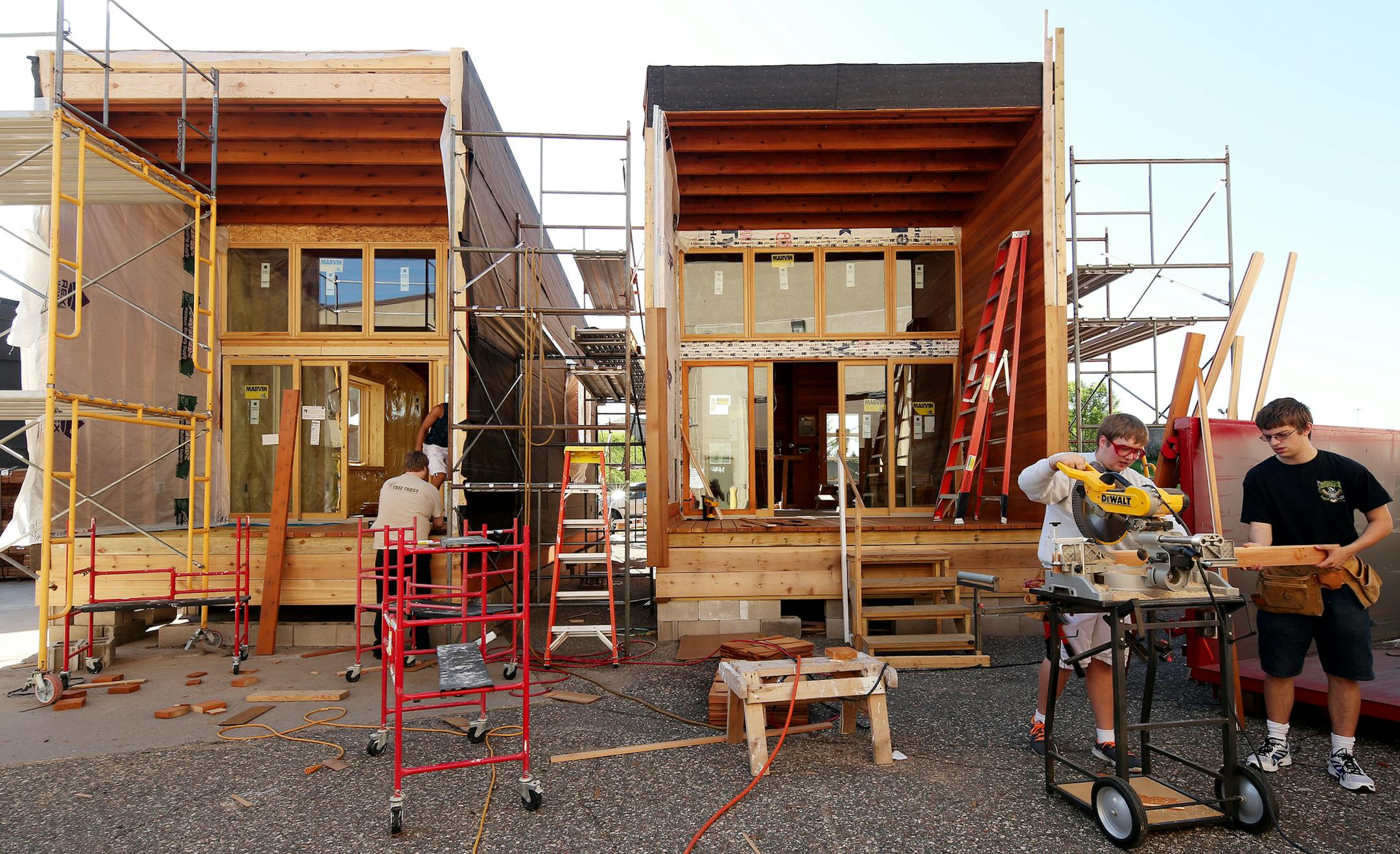 Right to left: Austin Long (black t-shirt), Zach Schulta (light colored sweat shirt), Santana Perdomo ( dark shirt in background) and Chad Stubbs (light t-shirt in background) work on the new camper cabins for Whitetail Woods Regional Park at Dakota Technical College. ] JOELKOYAMA‚Ä¢jkoyama@startribune Rosemount, MN on June 2, 2014. Camper cabins are being made by high school students at the Dakota Technical College for the new Whitetail Woods Regional Park which will open in Se