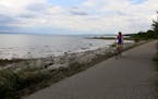 Margy Umhoefer of Sauk Centre, Minnesota, bikes along the shore of Little Traverse Bay on the Little Traverse Wheelway between Petoskey and Charlevoix