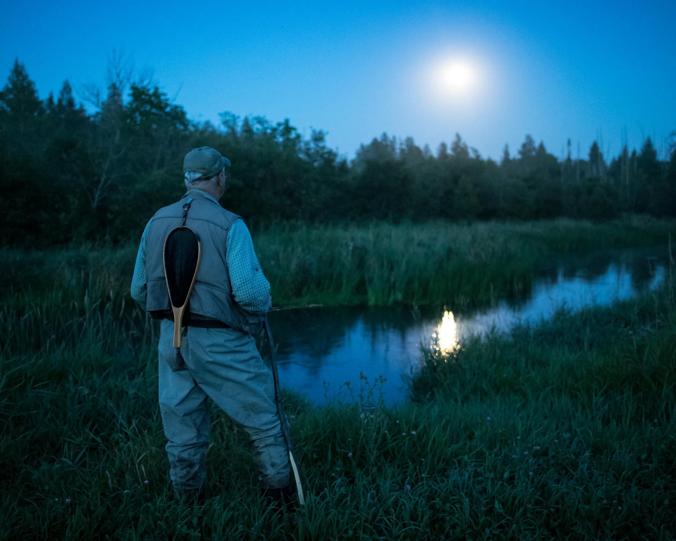 An angler checks for water disturbances on the Straight River while preparing to fish for brook trout.