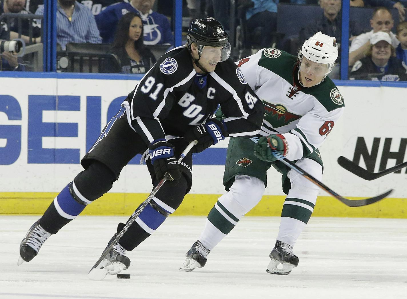 Tampa Bay Lightning center Steven Stamkos (91) moves the puck around Minnesota Wild center Mikael Granlund (64), of Finland, during the first period of an NHL hockey game Saturday, Nov. 22, 2014, in Tampa, Fla. (AP Photo/Chris O'Meara)