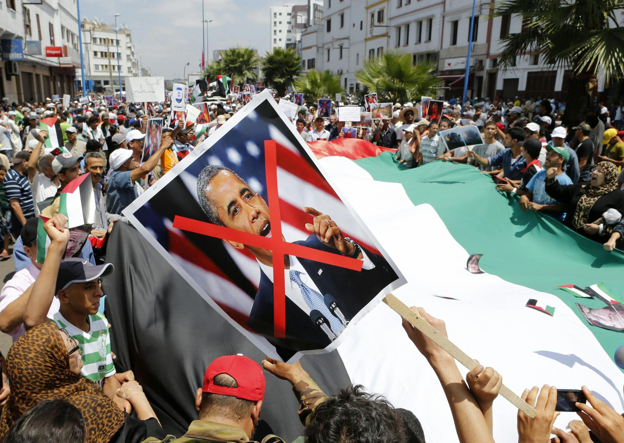A Palestinian flag and a poster of Barack Obama are displayed as thousands of pro-Palestinian demonstrators shout anti-Israeli slogans, during a protest against the Israeli offensive on the Gaza Strip in the streets of Casablanca, Morocco, Sunday, July 27, 2014.