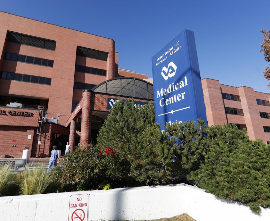 Blue sign says "Department of Veterans Affairs Medical Center" in front of brick building.