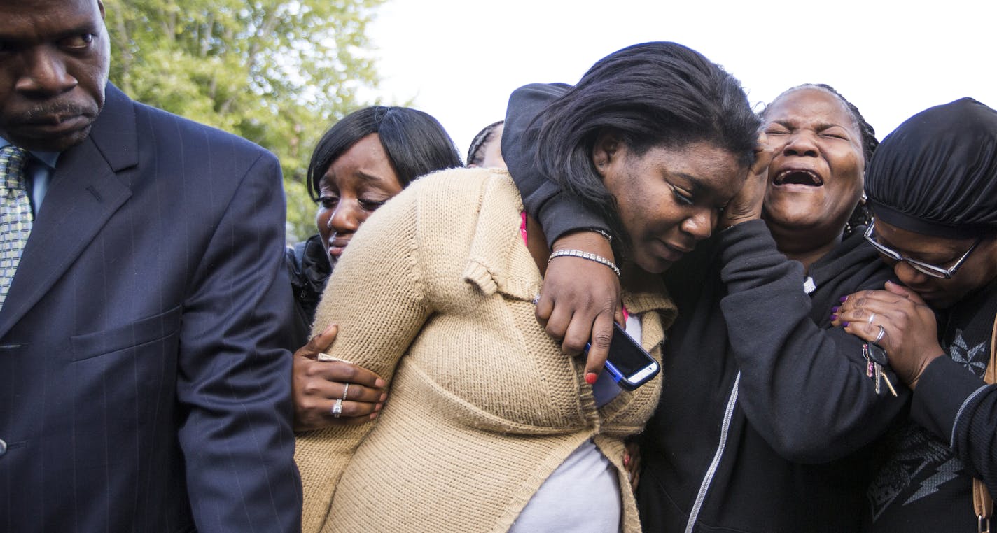 The mother of three children who died in a house fire, in center in beige, cries with her mother and aunt during a prayer vigil outside the home in Minneapolis on Sunday, October 4, 2015.