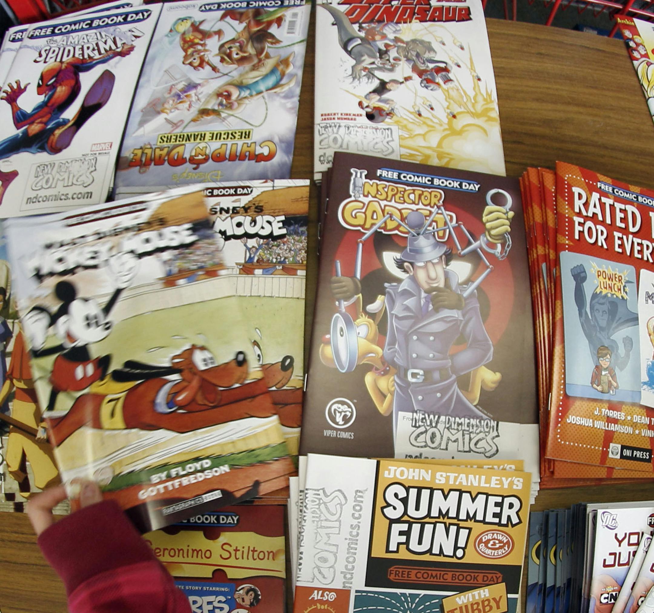 Nine-year-old Grace Mitchell picks up a "Mickey Mouse" comic book as she looks over the free comic books available at the New Dimensions Comics store on Free Comic Book Day, Saturday, May 7, 2011 in Cranberry, Pa. Grace came to the store with her twin sister, Megan, last year as well to take advantage of the annual give away.(AP Photo/Keith Srakocic)