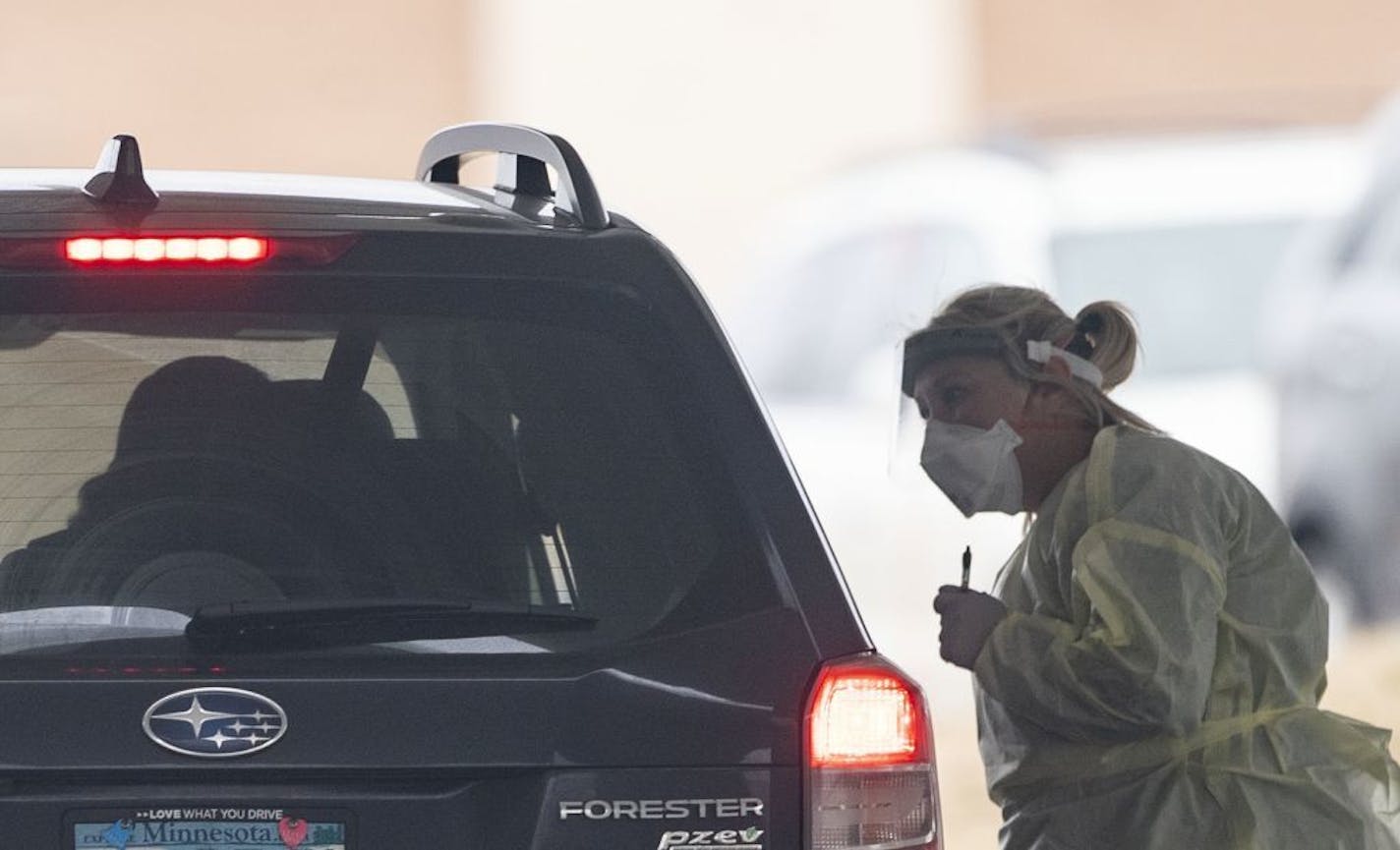 A Mayo Clinic employee dressed in protective gear spoke to a person in a drive thru coronavirus testing site under a tent set up in the parking lot of the Mayo Family Clinic Northwest on Thursday.