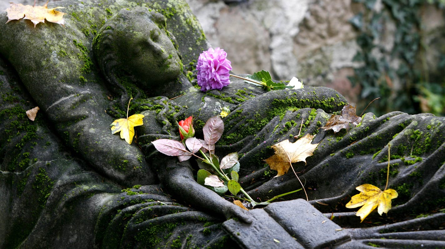 Autum leaves and flowers lay on the sculpture of a grave monument at the Old Cemetery in Freiburg, southern Germany, on Monday, Oct. 30, 2006. People in catholic dominated countries on All Saints Day, Wednesday, Nov. 1, 2006 traditionally remember their passed beloved. (AP Photo/Winfried Rothermel)